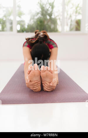 Giovani attraenti yogi donna a praticare yoga concetto, in seduta Janu Sirsasana esercizio, testa a ginocchio piegare in avanti pone, lavorando da indossare nero spo Foto Stock