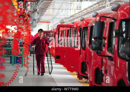--FILE--un lavoratore cinese passeggiate passato vetture essendo montati sulla linea di montaggio in corrispondenza di un impianto automatico di JAC (Cina Anhui Jianghuai Automobile Co., Ltd.) Foto Stock
