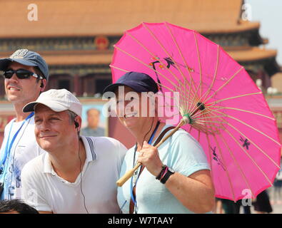 I turisti stranieri proteggersi con ombrelli e cappelli dal sole cocente come visiteranno la Piazza Tian'anmen a Pechino, in Cina, il 20 maggio 2017. Foto Stock