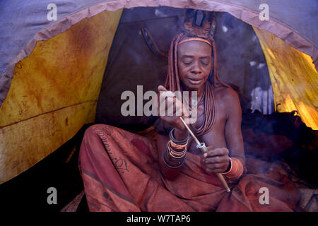 Donna Himba sbuffare nasale di tabacco da fiuto in tenda da campeggio e villaggio Himba, Kaokoland, Namibia, settembre 2013. Foto Stock