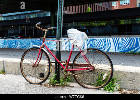 Vecchio abbandonato bicicletta rossa accanto al ponte stradale accanto a Manhattan, New York City, Stati Uniti d'America Foto Stock