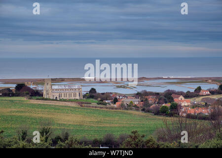 Vista verso la chiesa di San Nicola, con pascoli inondati di palude e violato le scandole di difesa costiera dopo il 6 dicembre east coast picchi di marea in background, Salthouse, Norfolk, Inghilterra, Regno Unito, dicembre 2013. Foto Stock
