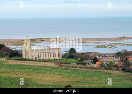 Vista verso la chiesa di San Nicola, con pascoli inondati di palude e violato le scandole di difesa costiera dopo il 6 dicembre east coast picchi di marea in background, Salthouse, Norfolk, Inghilterra, Regno Unito, dicembre 2013. Foto Stock