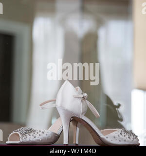 Brides scarpe con la riflessione di vestire in background sul suo giorno di nozze, sposa fotografia prep Foto Stock