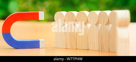 Figure in legno di persone e di un magnete. Gestione dei Team concetto. Risorse umane. Promuovere. La scelta di un nuovo leader e di assunzione dei dipendenti al lavoro. Headhunt Foto Stock
