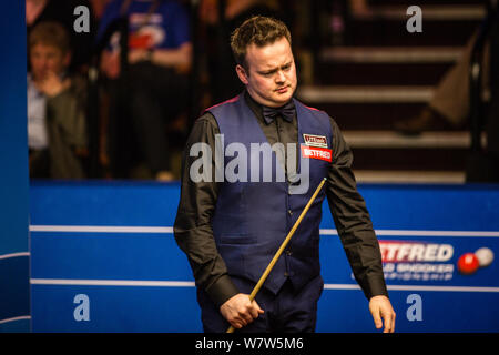 Shaun Murphy di Inghilterra ritiene un colpo a Yan Bingtao della Cina per il loro match di primo turno durante il 2017 Betfred World Snooker Championship presso il Foto Stock