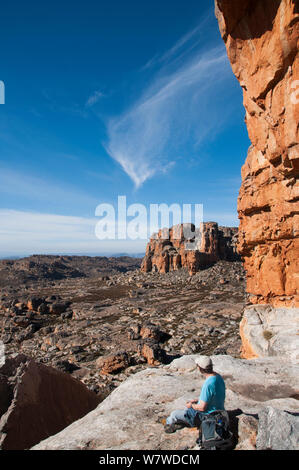 Vista da Wolfberg crepe e arco con uomo seduto sulla roccia, Cederberg Conservancy, Sud Africa, Agosto 2011. Foto Stock