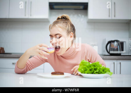 Concetto di dieta. Giovane donna scegliere tra frutta e dolci Foto Stock