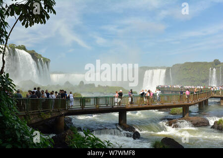 I turisti sul ponte osservando Iguasu Falls, Iguasu National Park, Brasile, aprile 2013. Foto Stock