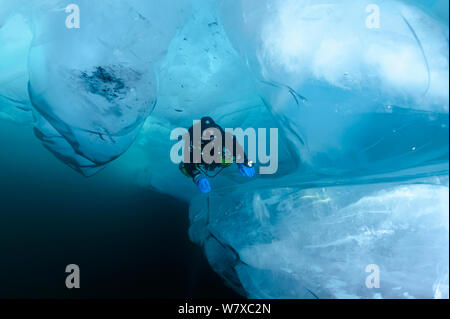 Diver esaminando rotto formazioni di ghiaccio sott'acqua. Lago Baikal, Russia, marzo 2013. Foto Stock