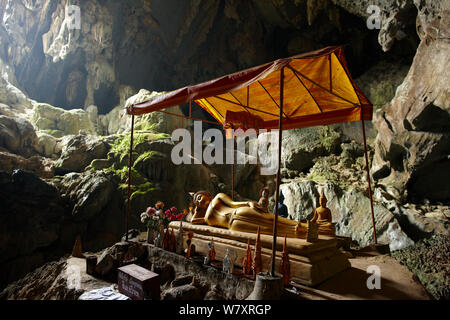 Statua del Buddha reclinato con piccole statue intorno in una grotta e la laguna blu, vicino a Vang Vieng, Laos, marzo 2009. Foto Stock