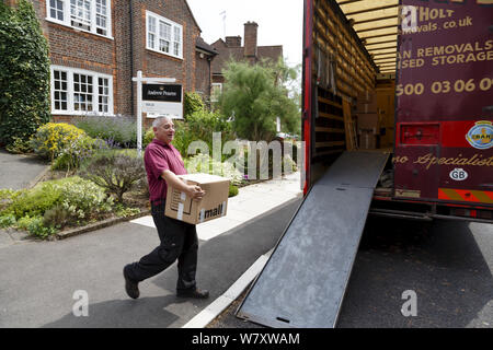 London, Regno Unito - 21 luglio 2014. Distacco uomo che porta una scatola di un autocarro di rimozione al di fuori di una casa a Londra, Regno Unito Foto Stock