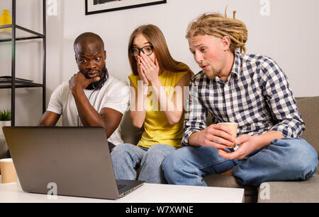 Schocked gruppo di amici a guardare intresting scary movie su laptop Foto Stock