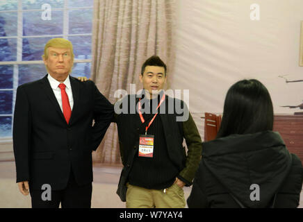 Un visitatore pone per le foto con una cera la figura del nuovo presidente americano Donald Trump sullo schermo durante una mostra nella città di Shenyang, a nord-est della Cina di Liao Foto Stock