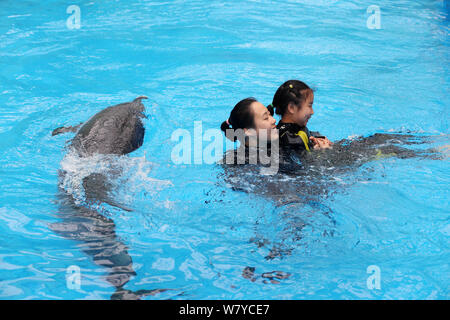 Cinese bambina autistica Chenchen interagisce con un delfino sotto la guida di un trainer a Chengdu Haichang Polar Ocean Park nella città di Chengdu, southwest ch Foto Stock