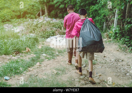 Gli studenti di sesso maschile aiutano a rimuovere i rifiuti dalla classe al mucchio di rifiuti. Messa a fuoco selettiva su nero garbage bag. Foto Stock