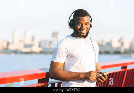 Nero runner sorridenti pronti per la formazione, tenendo il cellulare Foto Stock