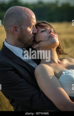 Coppia romantica nel giorno di nozze godendo la luce del tramonto in faccia Foto Stock