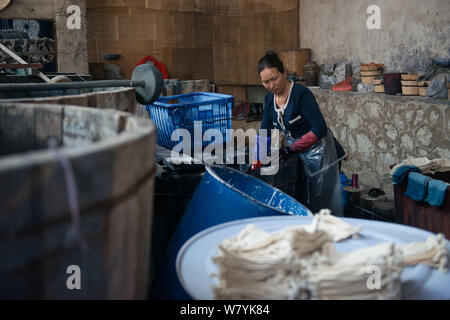 Una donna cinese Impregna i panni legato per la tintura nei secchi fino a far loro assumere la corretta indigo ombra di Dali, a sud-ovest della Cina di Yunnan provi Foto Stock