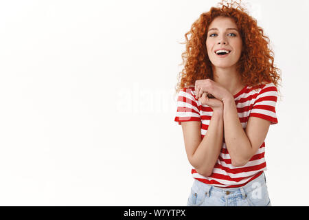 Buona femminile-cercando curly redhead ginger girl look scherzoso premere positivo palms grati insieme apprezzare il bel gesto di ridere felice di ricevere l Foto Stock