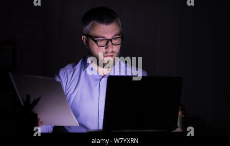 Uomo caucasico è lavorare con documenti, utilizzando laptop Foto Stock