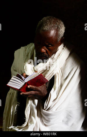 Sacerdote leggendo la Bibbia in Bet chiesa Maryaml (parte della Northwestern gruppo di chiese di Lalibela). UNESCO - Sito Patrimonio dell'umanità. Lalibela. Etiopia, dicembre 2014. Foto Stock