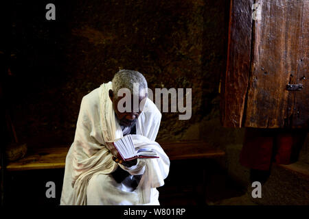 Sacerdote leggendo la Bibbia in Bet Maryam chiesa (parte della Northwestern gruppo di chiese di Lalibela). UNESCO - Sito Patrimonio dell'umanità. Lalibela. Etiopia, dicembre 2014. Foto Stock