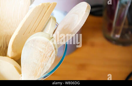 Vista ravvicinata di un gruppo di cucina in legno utensili dentro un contenitore di vetro. In cucina con utensili tradizionali Foto Stock