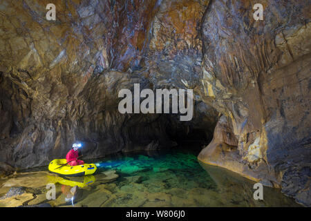 L'uomo esplorare laghi sotterranei via barca rigida gonfiabile, Croce grotta (Krizna jama) sotto il monte Croce, Verde Carso, Slovenia, ottobre 2014. Foto Stock