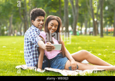 Romantica teenager tenendo selfie su una data nel parco Foto Stock