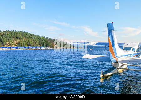 Un aereo marino si trova in acqua ancorata in una baia vicino a un porto turistico e resort presso il lago Coeur d'Alene, Idaho, con Tubs Hill sullo sfondo. Foto Stock