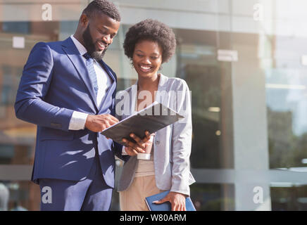 Coppia felice di African American business partner di lavoro permanente, mentre all'aperto, a discutere di un nuovo progetto. Sfocare lo sfondo con spazio di copia Foto Stock