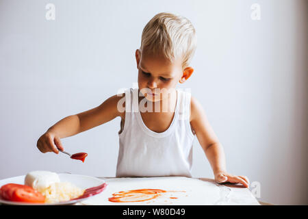 Funny happy chef boy cucinare la pizza a casa a tavola Foto Stock