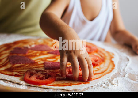 Funny happy chef boy cucinare la pizza a casa a tavola Foto Stock