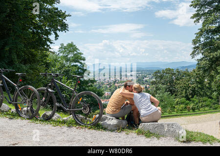 Lubiana, Slovenia. Il 3 agosto 2019. Un giovane seduto davanti al panorama visto dalla collina del castello della città Foto Stock