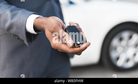 Afro man tenendo premuto i tasti con auto di colore bianco su sfondo Foto Stock