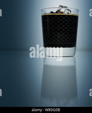 Caffè ghiacciato in elegante calice isolato su sfondo blu scuro Foto Stock