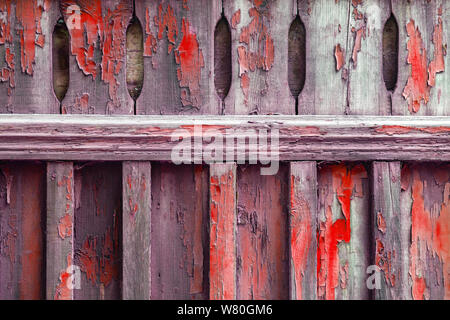 Vecchia staccionata in legno sporcato con peeling vernice rossa. Disegno astratto dello sfondo. Foto Stock