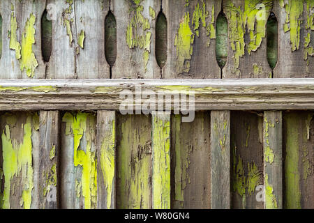 Vecchia staccionata in legno sporcato con peeling vernice verde. Disegno astratto dello sfondo. Foto Stock