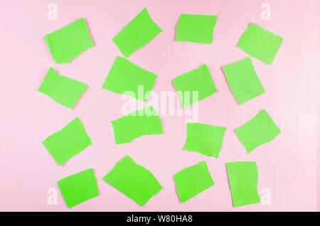 Sfondo astratto con pezzi strappati di carta verde sullo sfondo rosa. series photo Foto Stock