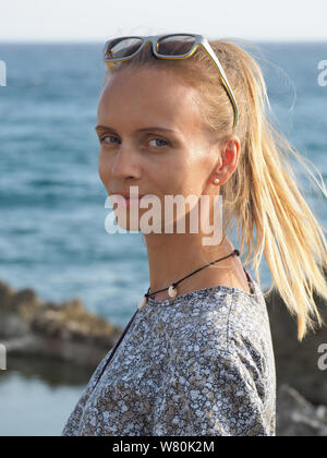 Ritratto della donna in posa durante il tramonto sullo sfondo dell'Oceano Atlantico. Foto Stock