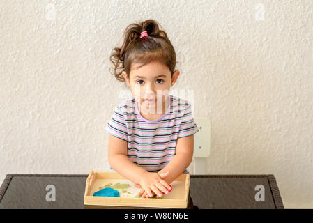 Carino bambina stampi da argilla colorato o di plastilina sul tavolo. Foto Stock