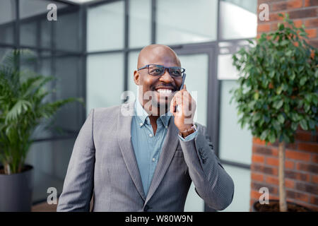 Imprenditore sorridente mentre si parla al telefono con la moglie Foto Stock