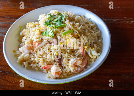 Asian Thai Seafood riso fritto con gamberetti e calamari sul piatto bianco e ruvido tabella. Foto Stock