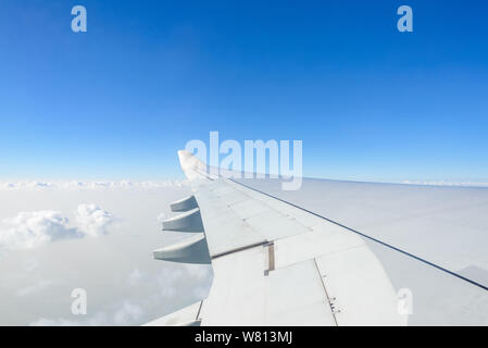 Cancellare il profondo blu del cielo sopra uno strato dello spessore di nuvole mosse al Stratosphere atmosfera visto dall aereo finestra situata al di sopra del velivolo ala e jet. Foto Stock