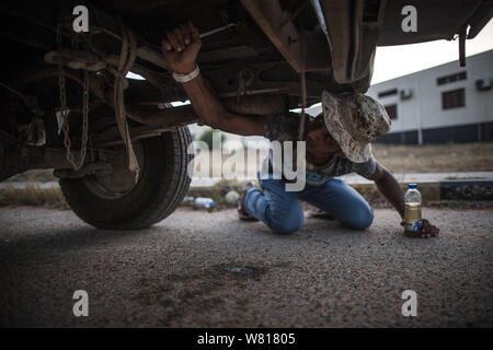 Tripoli, Libia. Il 7 agosto, 2019. Un combattente dell'ONU-backed Governo di intesa nazionale (GNA) Correzioni di un veicolo danneggiato in un campo vicino alla Salah Al-Din frontline a Tripoli, in Libia, il 7 agosto, 2019. La Libia è stata coinvolta in conflitti e caos mai poiché la caduta dell ex leader Muammar Gheddafi nel 2011. Credito: Amru Salahuddien/Xinhua Foto Stock