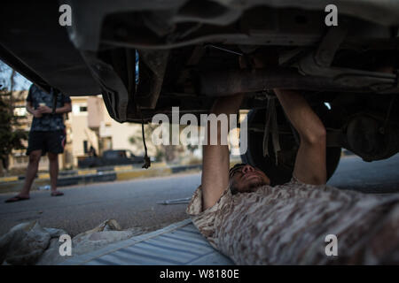 Tripoli, Libia. Il 7 agosto, 2019. Un combattente dell'ONU-backed Governo di intesa nazionale (GNA) Correzioni di un veicolo danneggiato in un campo vicino alla Salah Al-Din frontline a Tripoli, in Libia, il 7 agosto, 2019. La Libia è stata coinvolta in conflitti e caos mai poiché la caduta dell ex leader Muammar Gheddafi nel 2011. Credito: Amru Salahuddien/Xinhua Foto Stock