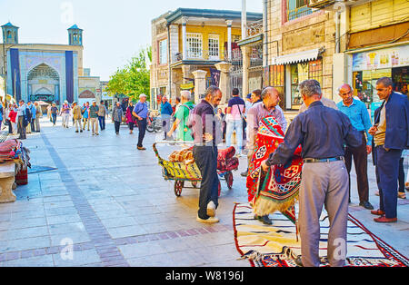 SHIRAZ, IRAN - 14 ottobre 2017: la trafficata strada di Vakil Bazaar, i portieri, i fornitori e i mercanti tappeto a controllare la qualità dei grandi tappeti, su Octo Foto Stock