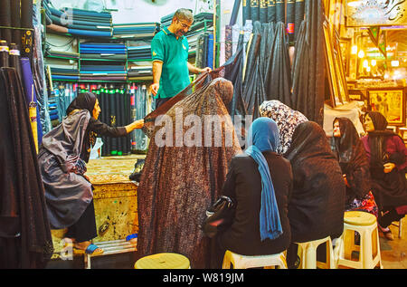 SHIRAZ, IRAN - 14 ottobre 2017: Il gruppo di persone anziane donne musulmane hanno scelto di tessuto nero per il chador nel negozio di Vakil Bazaar, il 14 ottobre in Shiraz Foto Stock