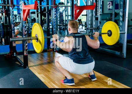 Atleta svolge l'esercizio squat con barbell in palestra Foto Stock
